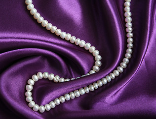 Image showing White pearls on a lilac silk as background 