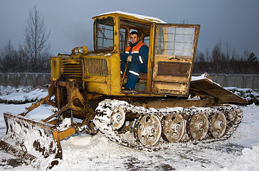 Image showing The tractor driver cleans snow