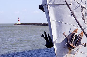 Image showing Ship with raised anchor closeup and red lighthouse