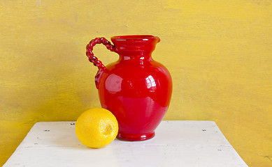 Image showing Still life. Red vase and yellow lemon on a shelf
