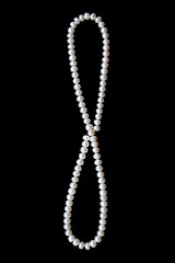 Image showing White pearls on the black silk as background 