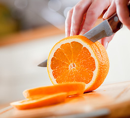 Image showing Woman's hands cutting orange