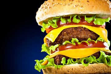 Image showing Tasty and appetizing hamburger on a dark blue