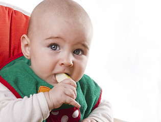 Image showing baby sitting and eating an apple