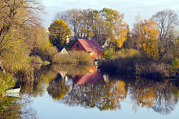 Image showing Village houses near river. Autumn trees water boat