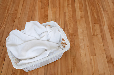 Image showing White towels in a laundry basket on wooden floor