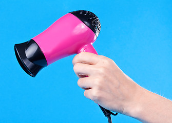 Image showing Pink hair dryer in the female hand
