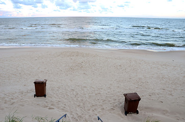 Image showing Garbage containers sea sand waves backdrop 