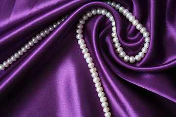 Image showing White pearls on a lilac silk as background 