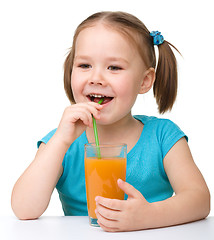 Image showing Little girl drinks orange juice