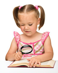 Image showing Little girl play with book and magnifier