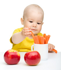 Image showing Little boy pulling up carrot from a cup