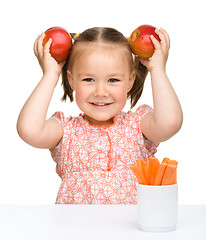 Image showing Cute little girl eats carrot and apples