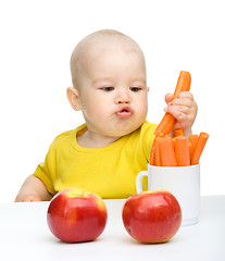 Image showing Little boy pulling up carrot from a cup