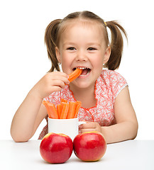 Image showing Cute little girl eats carrot and apples