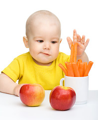 Image showing Little boy pulling up carrot from a cup