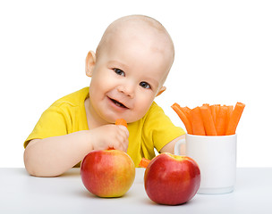 Image showing Cute little boy eats carrot and apples