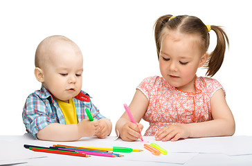 Image showing Two children are drawing on paper using markers