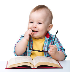 Image showing Little child play with book and glasses