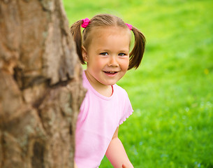 Image showing Little girl is playing hide and seek outdoors