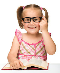 Image showing Little girl is flipping over pages of a book