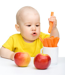 Image showing Little boy pulling up carrot from a cup