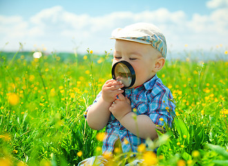 Image showing Little boy is playing with magnifier