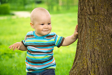 Image showing Little boy is playing hide and seek outdoors