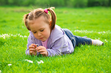 Image showing Little girl is laying on green meadow