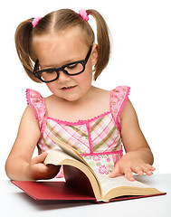 Image showing Little girl is flipping over pages of a book