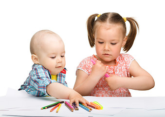 Image showing Two children are drawing on paper using markers