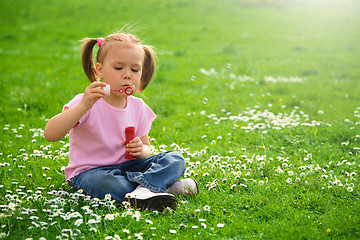 Image showing Little girl is sitting on green meadow