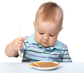 Image showing Cute little boy is playing with fruit puree