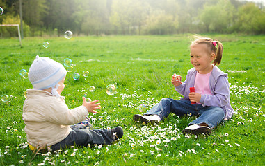 Image showing Two children are sitting on green meadow