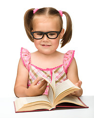 Image showing Little girl is flipping over pages of a book