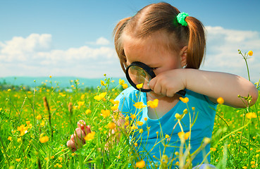 Image showing Little girl examining flowers using magnifier