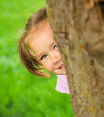 Image showing Little girl is playing hide and seek outdoors