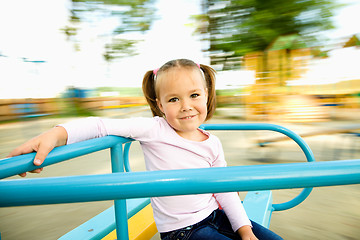 Image showing Cute little girl is riding on merry-go-round