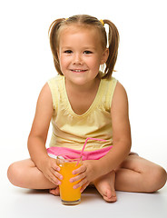 Image showing Little girl drinks orange juice