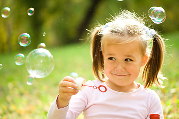 Image showing Little girl is blowing a soap bubbles