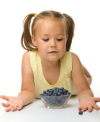 Image showing Cute little girl is eating blueberry