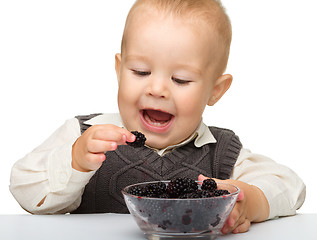 Image showing Little boy is eating blackberry