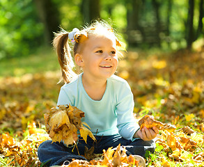 Image showing Little girl is playing in autumn park