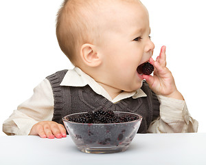 Image showing Little boy is eating blackberry