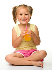 Image showing Little girl drinks orange juice