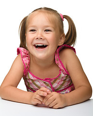 Image showing Happy little girl is sitting at the table