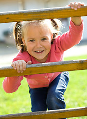 Image showing Cute little girl is climbing up on ladder