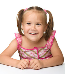 Image showing Happy little girl is sitting at the table