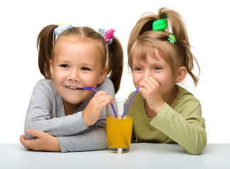 Image showing Two little girls are drinking orange juice