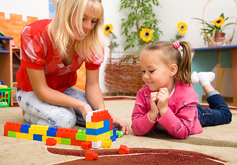Image showing Teacher and child are playing with bricks